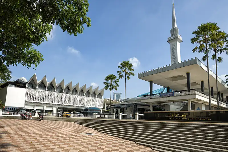 Malaysia National Mosque in Kuala Lumpur, featuring modern Islamic architecture and palm trees.