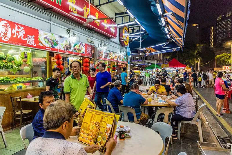 Jalan Alor in Kuala Lumpur, a bustling street food destination with diners enjoying local dishes at night.