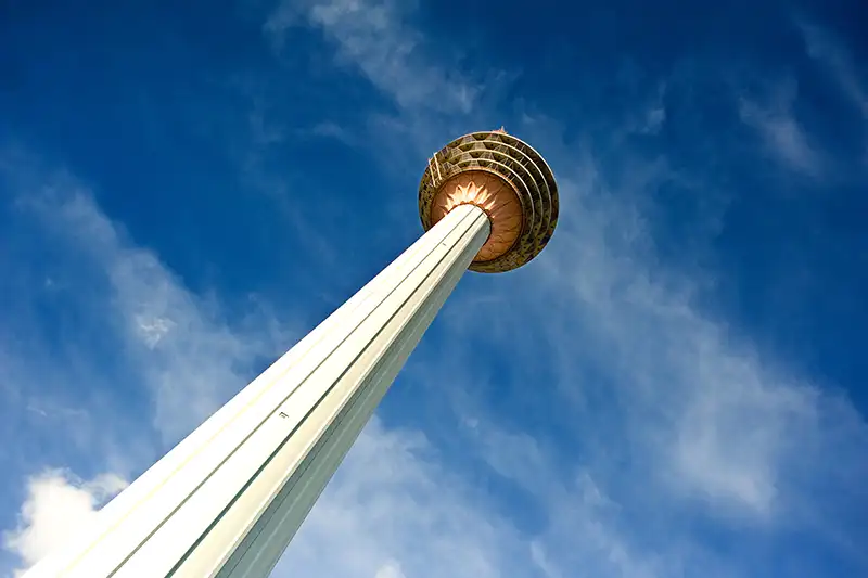 KL Tower in Kuala Lumpur against a bright blue sky, a popular tourist destination in Malaysia.
