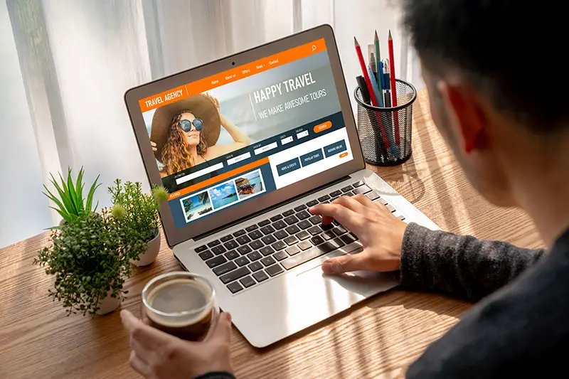 Tourist browsing a local travel agency website on a laptop, planning a cost-effective trip to Malaysia."