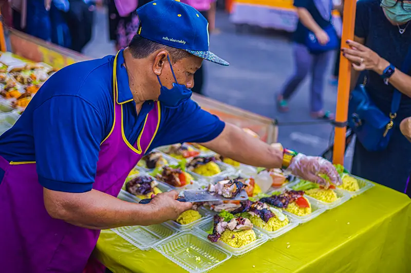 Street vendor in Malaysia serving homemade chicken rice, offering affordable and delicious meals for budget-conscious tourists.