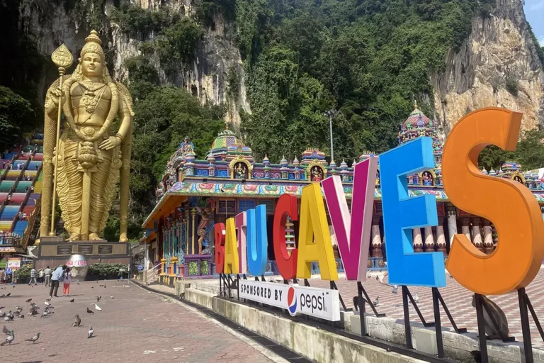 Golden Lord Murugan statue, colorful Batu Caves stairs, and vibrant temple exterior in Malaysia.