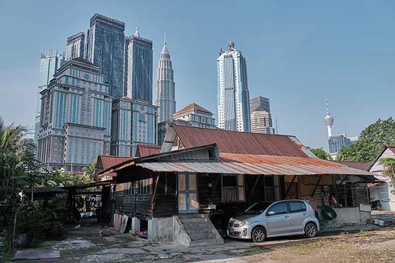 Traditional Malay house in Kampung Baru with Kuala Lumpur skyline in the background, showcasing cultural and modern contrasts