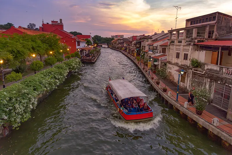 Melaka River Cruise during sunset with colorful buildings along the riverbank, a top attraction among top attractions in Malaysia