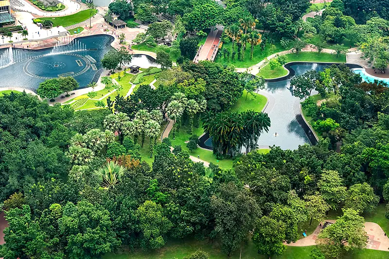 Aerial view of KLCC Park with lush greenery, lakes, and fountains, offering a serene escape near the Petronas Twin Towers in Kuala Lumpur, Malaysia