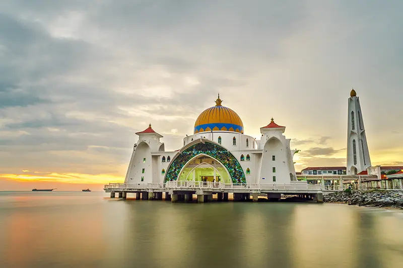 The Straits Mosque in Malacca, a stunning attraction visited during a Malacca day trip from Kuala Lumpur, offering scenic views of the sea and sunset.