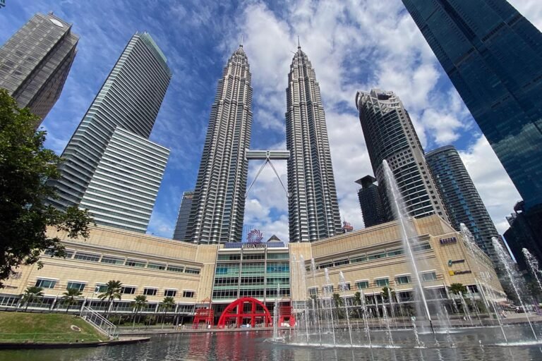 Petronas Twin Towers viewed from KLCC Park with fountain display and surrounding skyscrapers in Kuala Lumpur, Malaysia."