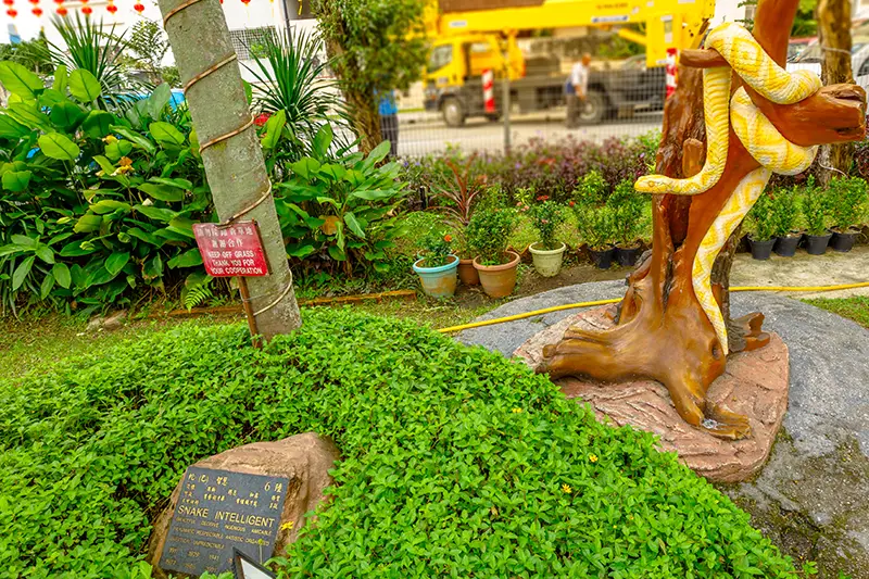 Snake zodiac statue at the Chinese Zodiac Park in Thean Hou Temple Kuala Lumpur, surrounded by greenery and signboard.