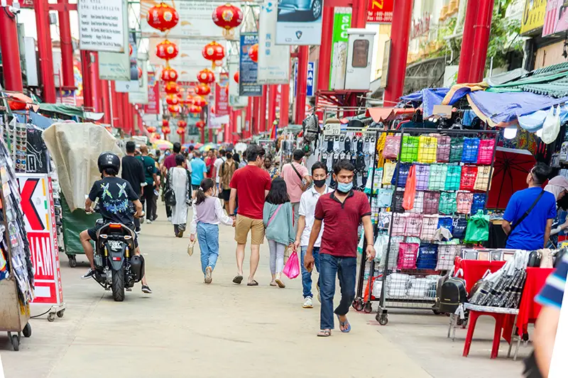 Busy afternoon in Kuala Lumpur’s Chinatown at Petaling Street, where tourists browse souvenir stalls and bargain for deals
