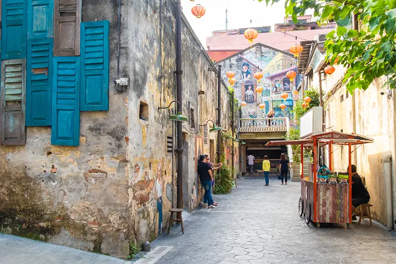 Tourists exploring Kwai Chai Hong alley near Chinatown Kuala Lumpur, featuring murals, lanterns, and restored heritage shophouses