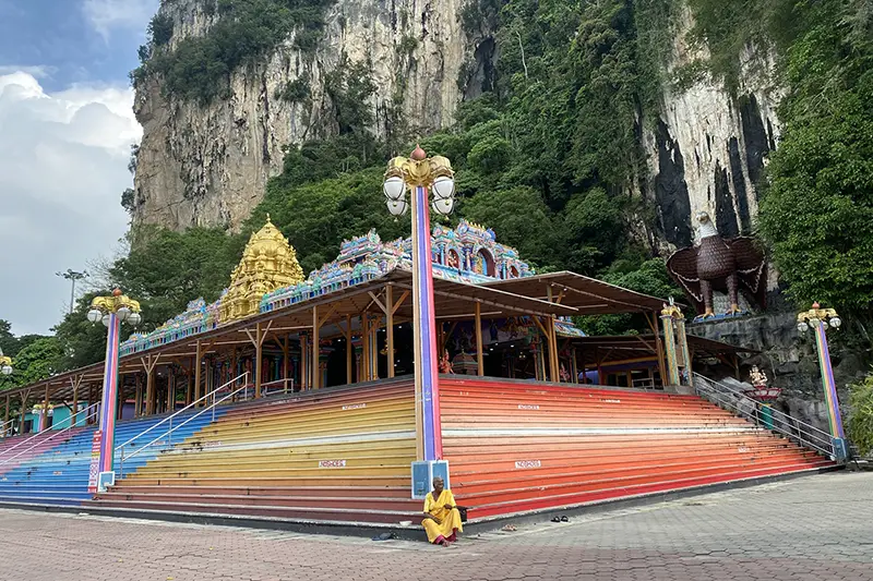 Colorful steps and Sri Venkatachalapathi Alamelu Temple at the base of Batu Caves, Malaysia, with limestone cliffs and greenery in the background