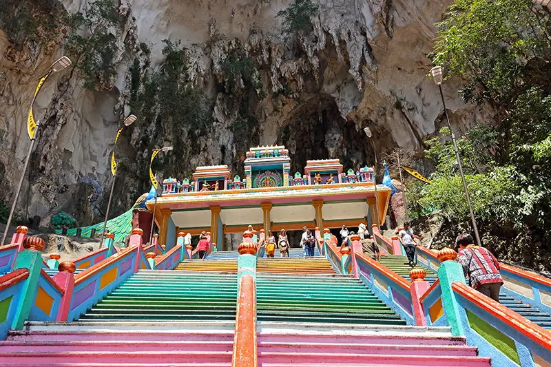 Colorful staircase and temple gopuram near the entrance of the upper cave at Batu Caves, with limestone cliffs and hanging stalagmites in the background—one of the best spots for a photo opportunity in Batu Caves.